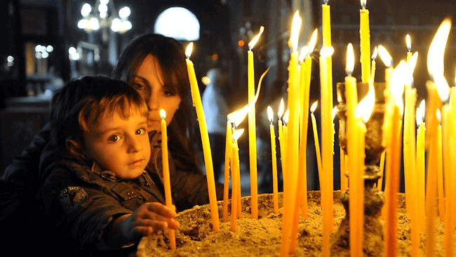 Trẻ em cùng ba mẹ thắp nến trong lễ phục sinh ở Hy Lạp